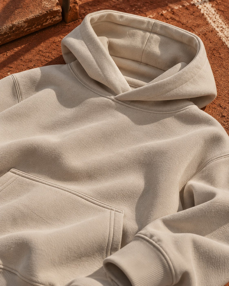Close-up of a cream Calcuera hoodie lying on a clay court