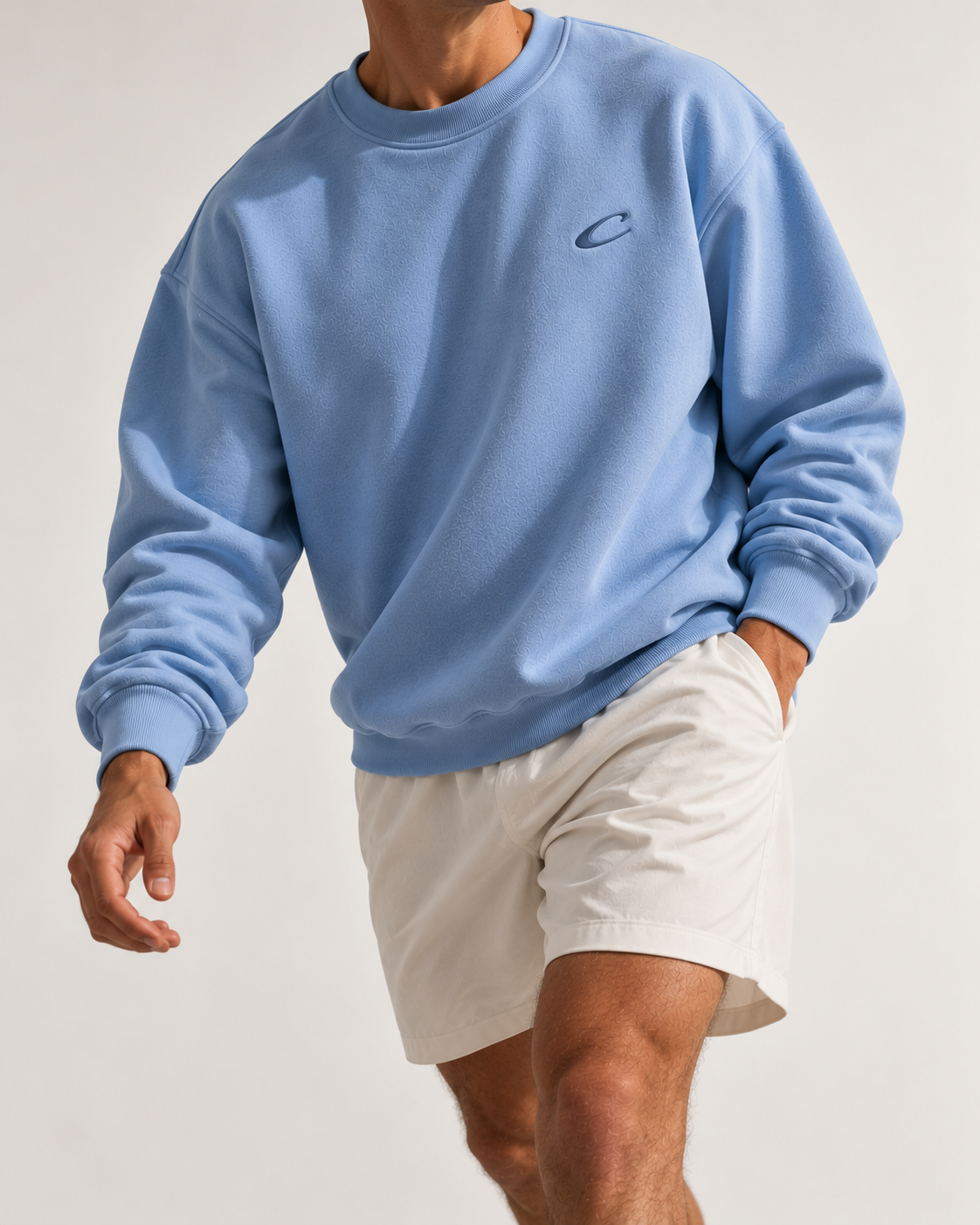 Man wearing the Calcuera Icon Sweatshirt in sky blue with off-white shorts